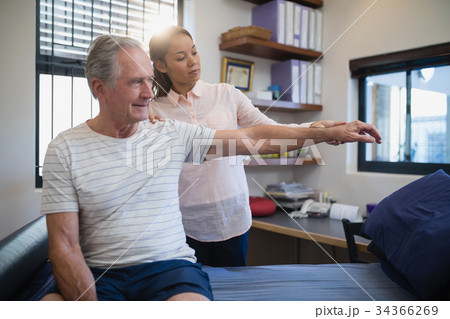 Female doctor and senior male patient looking at hand Female doctor and senior male patient looking at hand 34366269