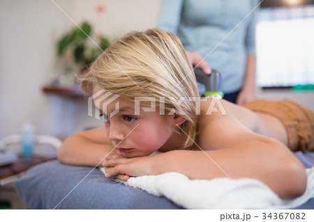 Close-up of boy lying on bed while female therapist using ultrasound machine 34367082