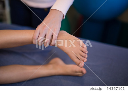 High angle view of female therapist examining feet with boy lying on bed 34367101