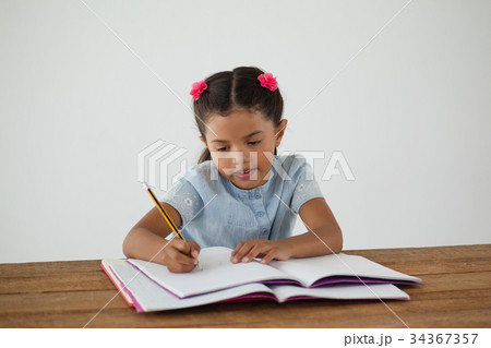 Young girl writing in her book against white background Young girl writing in her book against white background 34367357