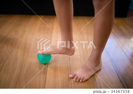 Low section of boy standing while stepping on stress ball 34367358