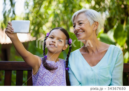 Smiling girl and grandmother taking selfie Smiling girl and grandmother taking selfie 34367680