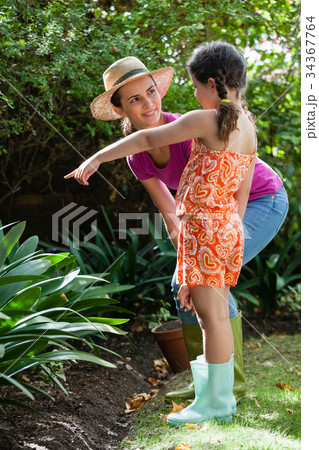 Mother looking at girl pointing by plants Mother looking at girl pointing by plants 34367764