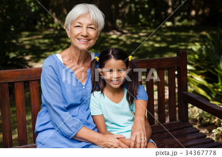 Portrait of senior woman with granddaughter sitting on wooden bench Portrait of senior woman with granddaughter sitting on wooden bench 34367778