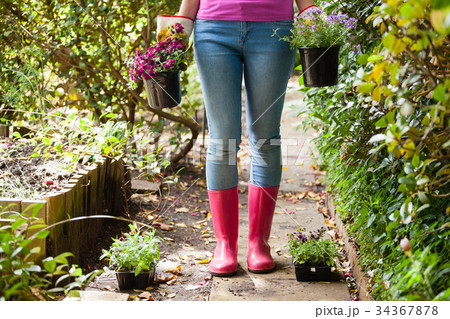 Low section of woman standing with potted plants on footpath 34367878