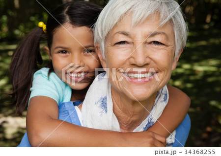 Close-up portrait of smiling grandmother giving piggyback to granddaughter Close-up portrait of smiling grandmother giving piggyback to granddaughter 34368255