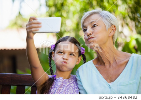 Girl and grandmother making faces while taking selfie 34368482