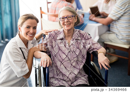 Portrait of smiling female doctor with disabled senior woman sitting on wheelchair 34369466