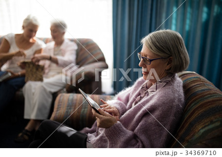 Senior woman using digital tablet while sitting on armchair 34369710
