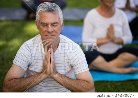 Senior man with eyes closed meditating in prayer position 34370077