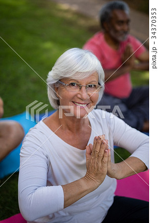 High angle view of smiling senior woman meditating in prayer position High angle view of smiling senior woman meditating in prayer position 34370353