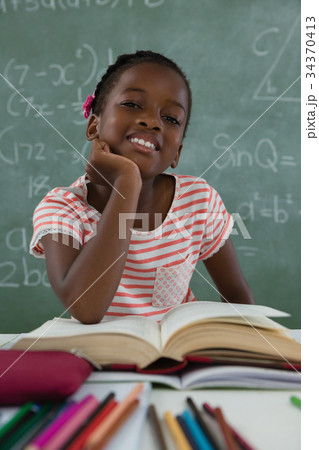 Schoolgirl reading book in classroom 34370413