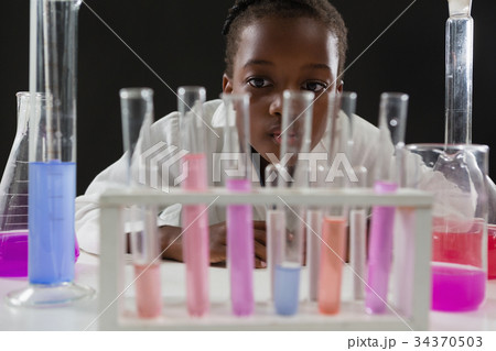 Schoolgirl doing a chemical experiment against black background Schoolgirl doing a chemical experiment against black background 34370503
