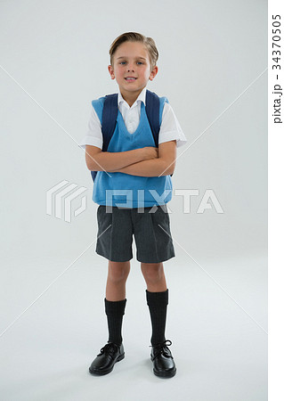Portrait of cute schoolboy standing with arms crossed Portrait of cute schoolboy standing with arms crossed 34370505