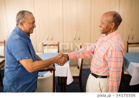 Smiling senior man doing handshake with friend Smiling senior man doing handshake with friend 34370506