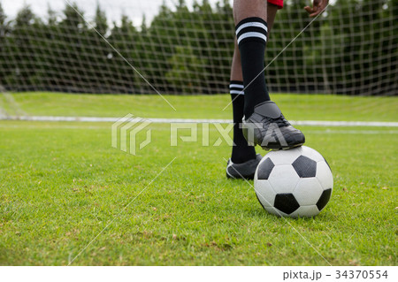Low section of male soccer player with ball on field 34370554