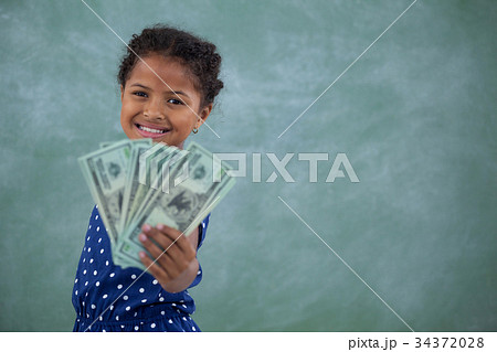 Portrait of happy girl showing paper currency 34372028