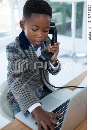 Businessman typing on laptop while using telephone 34372639