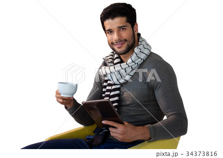 Portrait of man using digital tablet while having cup of tea 34373816