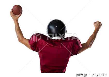 Rear view of sportsman holding football with arms raised Rear view of sportsman holding football with arms raised 34373848