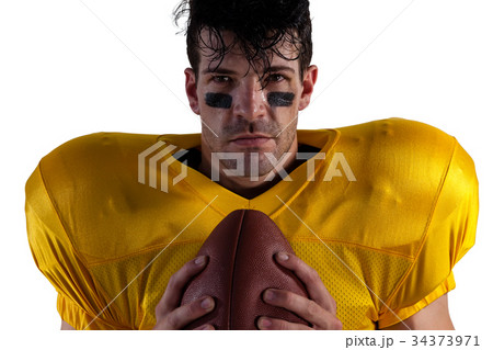 Portrait of determined American football player holding ball Portrait of determined American football player holding ball 34373971