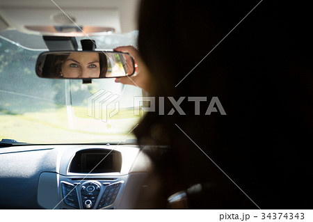 Woman looking into rear view mirror while driving a car 34374343