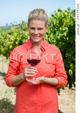 Portrait of female vintner holding glass of wine Portrait of female vintner holding glass of wine 34374504