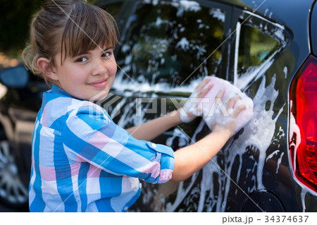 Teenage girl washing a car on a sunny day 34374637