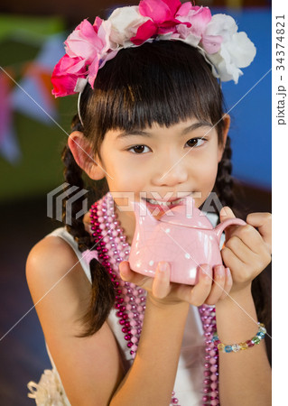 Portrait of cute girl holding toy teapot during birthday party 34374821