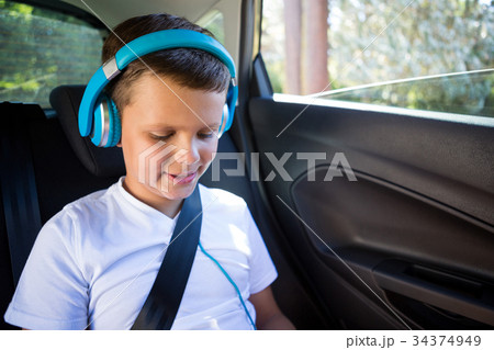 Teenage boy with headphones sitting in the back seat of car Teenage boy with headphones sitting in the back seat of car 34374949