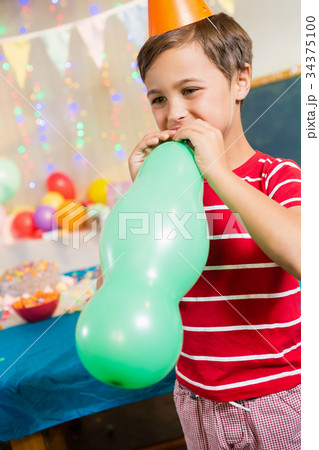 Cute boy blowing balloon during birthday party Cute boy blowing balloon during birthday party 34375100