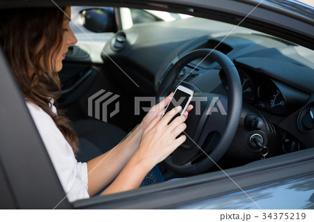 Woman using mobile phone while driving a car Woman using mobile phone while driving a car 34375219