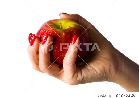 A female hand with red nails holds an apple. 34375226