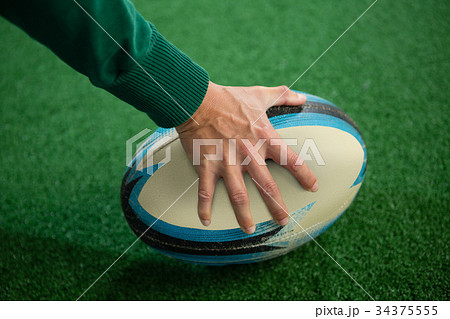 Cropped hand holding rugby ball 34375555