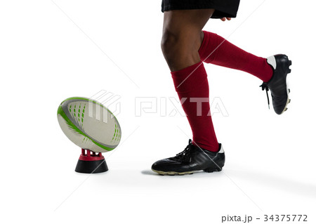 Low section of sportsman kicking rugby ball on tee Low section of sportsman kicking rugby ball on tee 34375772