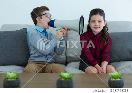 Businessman shouting through megaphone into female colleagues ear 34376333