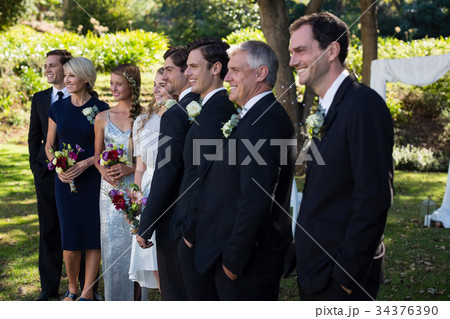 Happy bride and groom standing with guests 34376390