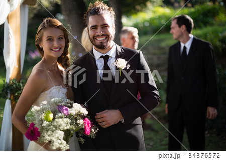 Happy bride and groom standing in park 34376572