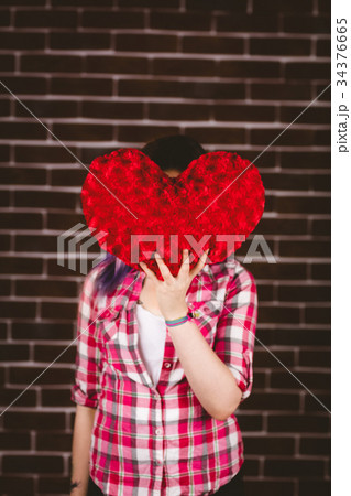 Woman hiding face from heart shape 34376665