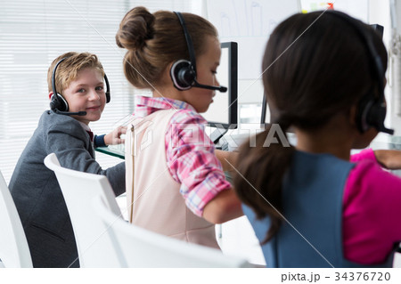 Boy as customer care executive smiling while working in the office Boy as customer care executive smiling while working in the office 34376720
