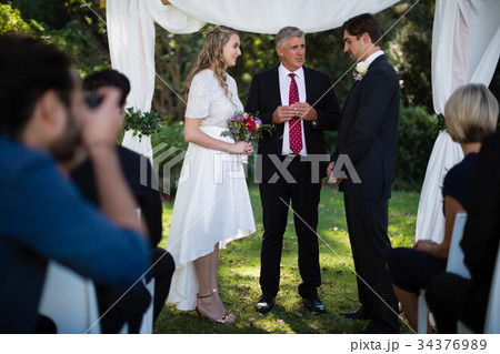 Minister giving speech to bride and groom Minister giving speech to bride and groom 34376989