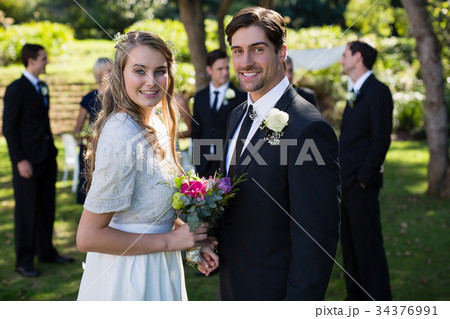 Happy bride and groom standing in park Happy bride and groom standing in park 34376991