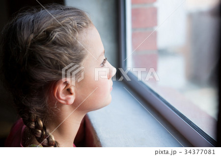 Thoughtful teenage girl looking through window 34377081