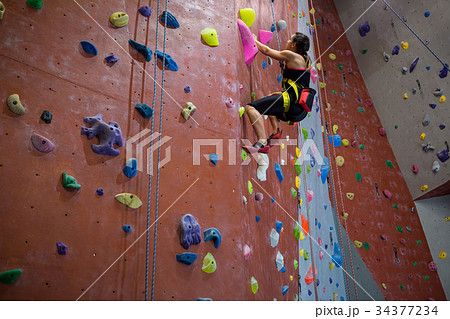 Woman practicing rock climbing in fitness studio Woman practicing rock climbing in fitness studio 34377234