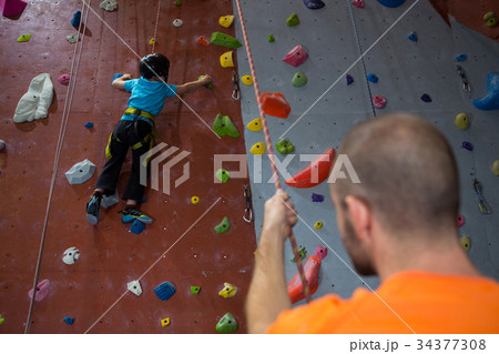 Trainer assisting boy in rock climbing Trainer assisting boy in rock climbing 34377308