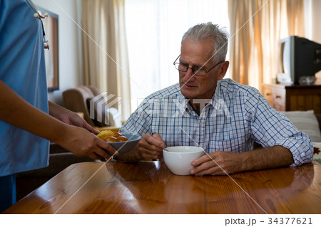 Female doctor serving food to senior man in nursing home Female doctor serving food to senior man in nursing home 34377621