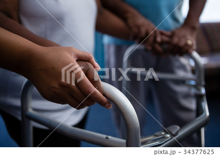 Cropped hands of nurse assisting woman in walking with walker 34377625