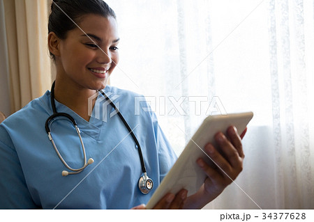 Smiling doctor using digital table in retirement home 34377628