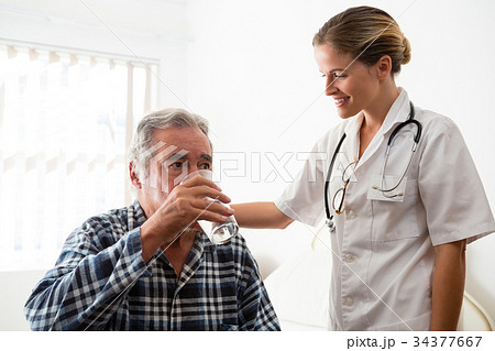 Female doctor standing by senior man drinking water 34377667