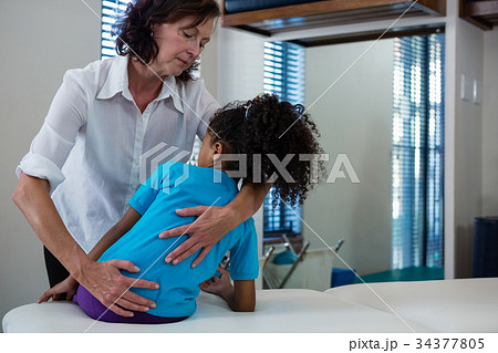 Physiotherapist giving back massage to girl patient Physiotherapist giving back massage to girl patient 34377805